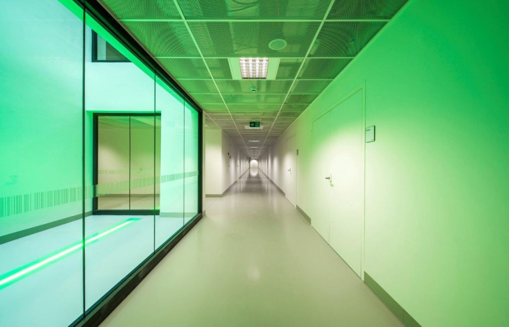 Hospital corridor with clean flooring and green light shining through glass