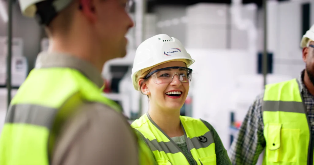 Two workers wearing hard hats featuring the McLoughlin Industrial Flooring logo